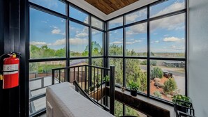 Ein Zimmer mit großen Fenstern und Blick auf eine Landschaft mit Bäumen und einem Gebäude.