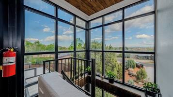 A room with large windows offering a view of a landscape with trees and a building.