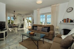 A living room with a sofa, coffee table, and a dining area with chairs and a table. - Los Olivos 3 Bedroom Villa with Heated Pool (Nerja)