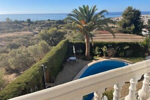 A pool with a view of the sea, a palm tree, and a well-maintained garden. - Los Olivos 3 Bedroom Villa with Heated Pool (Nerja)