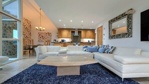 Una sala de estar moderna con un sofá blanco grande, una mesa de centro y un comedor con papel tapiz floral.