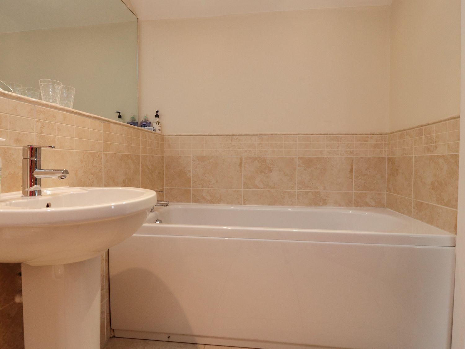 A bathroom with a sink, mirror, and bathtub.
