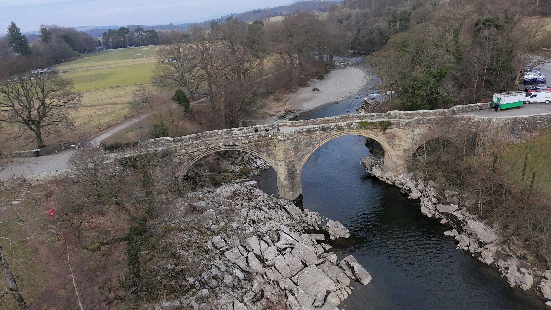 A stone bridge over a river with a road passing underneath.