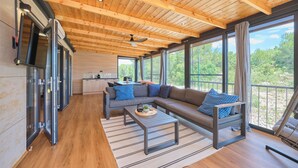 A modern living room with a wooden ceiling, large windows, a sofa, a coffee table, and a kitchen area. - MH Holiday Dream - Shining Sea - Oaza Mira campsite (Drage)