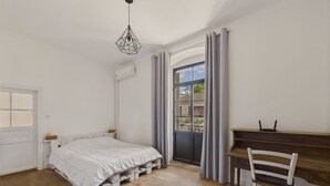 Ein Schlafzimmer mit Bett, Schreibtisch, Stuhl, Fenster und einer Pendelleuchte.