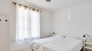 A bedroom with a bed, bedside tables, a wardrobe, and a window with curtains. - House for 6, garden & AC, walk everywhere (Barbâtre)