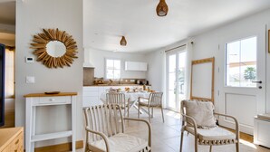 A modern kitchen with white cabinets, a wooden dining table, and a large window. - House for 6, garden & AC, walk everywhere (Barbâtre)