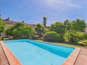 Relax by the pool surrounded by lush gardens and a deck.