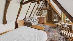 A rustic attic bedroom with exposed wooden beams, a bed, a dresser, and a chair. - Shared pool and wooded grounds - house for 4 (Montignac)
