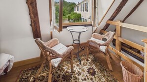 A cozy room with two wicker chairs, a small round table, and a view of a garden through a window. - Shared pool and wooded grounds - house for 4 (Montignac)