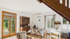 Un vaste espace de vie comprenant une table à manger, des chaises, un buffet en bois et un escalier.