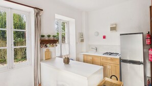 Une cuisine de taille réduite dotée d’un îlot central, de meubles en bois, d’une cuisinière à gaz et d’un réfrigérateur.