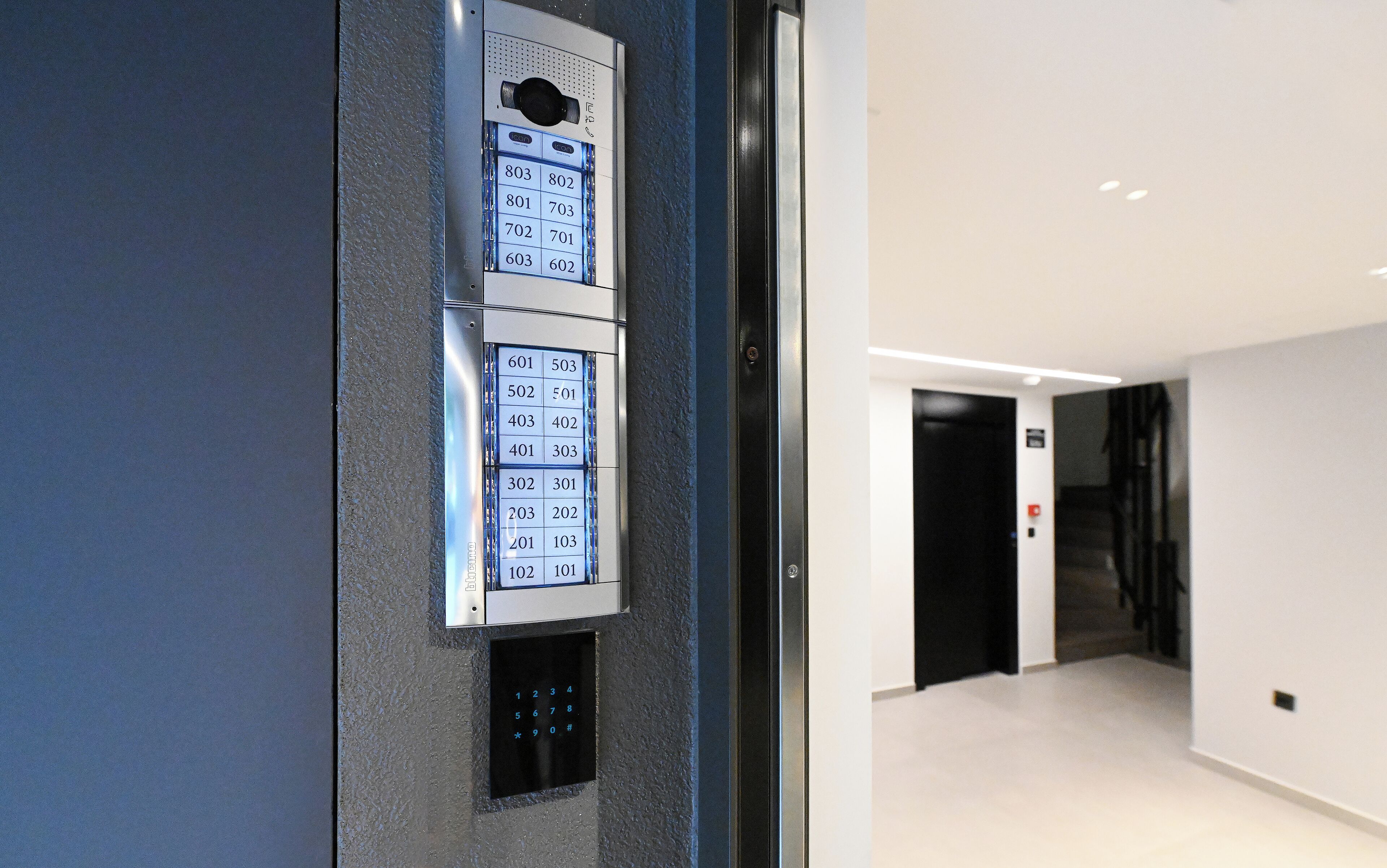 A wall-mounted elevator control panel with a numerical keypad and a small display.