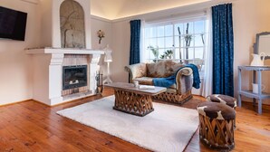 Una sala de estar con chimenea, un sofá, una mesa de centro y una alfombra.