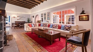 Amplia sala de estar con techo de madera, un conjunto de sofás, una mesa de centro y una chimenea.