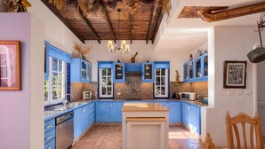 Una cocina con armarios azules, techo de madera y piso de baldosas.