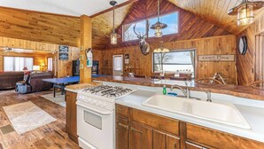 A rustic cabin interior with a kitchen, dining area, and living room.