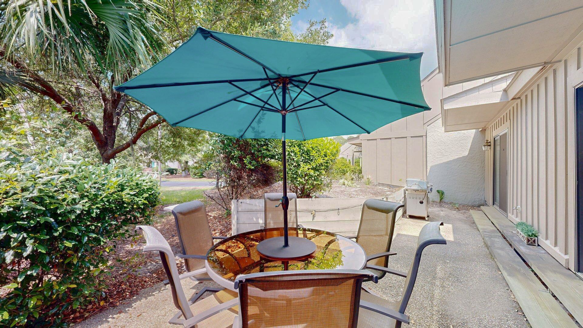 An outdoor patio with a round table, four chairs, and a large umbrella.