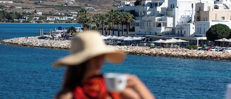 A coastal view with white buildings and a blue dome, a dining table with food, and a person in a hat.