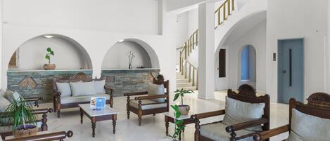 A spacious lobby with a high ceiling, wooden furniture, and a stone wall.