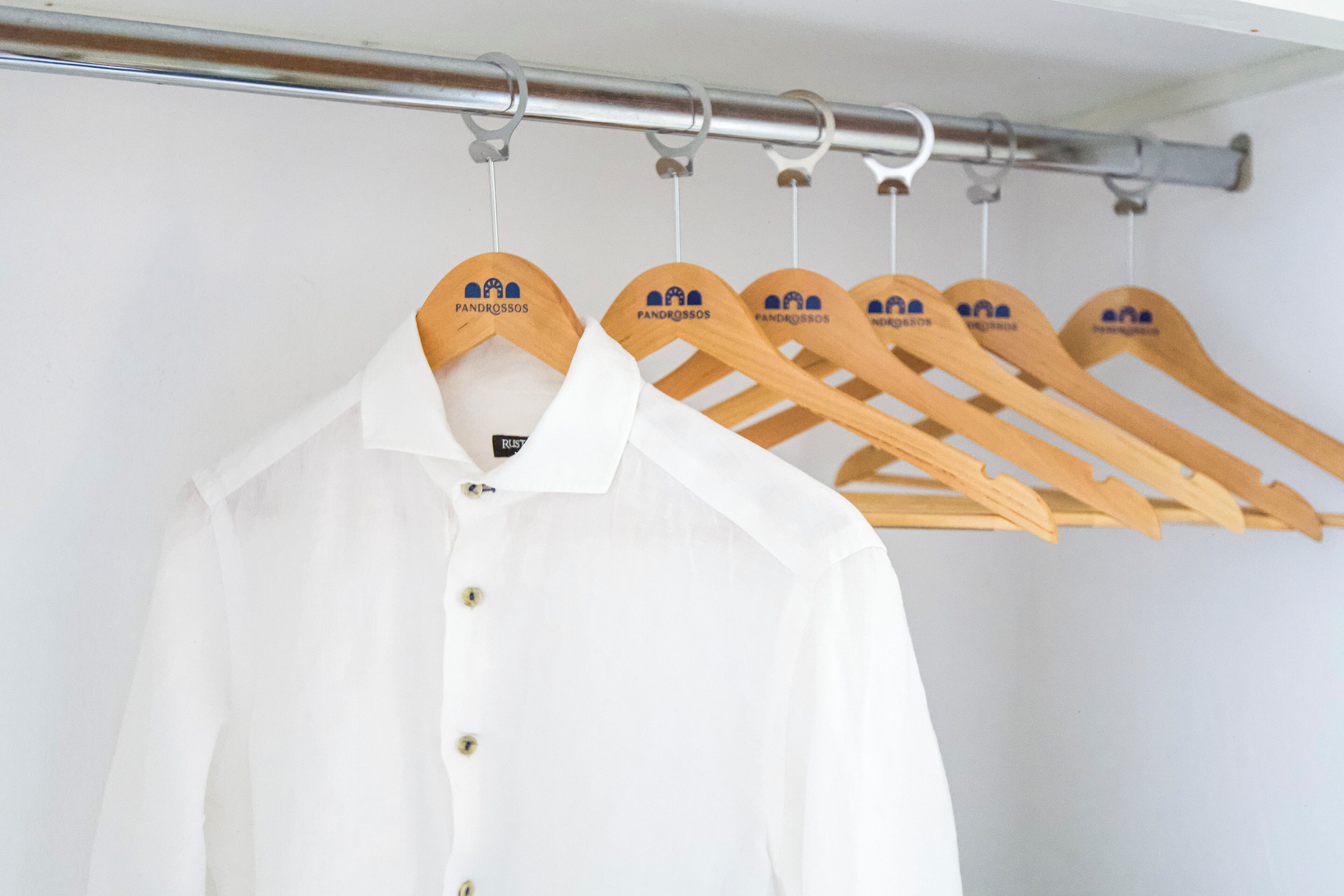 A white shirt hanging on a wooden hanger with a logo.