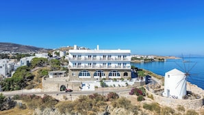 Un hotel con fachada blanca, varios balcones y vista al mar.