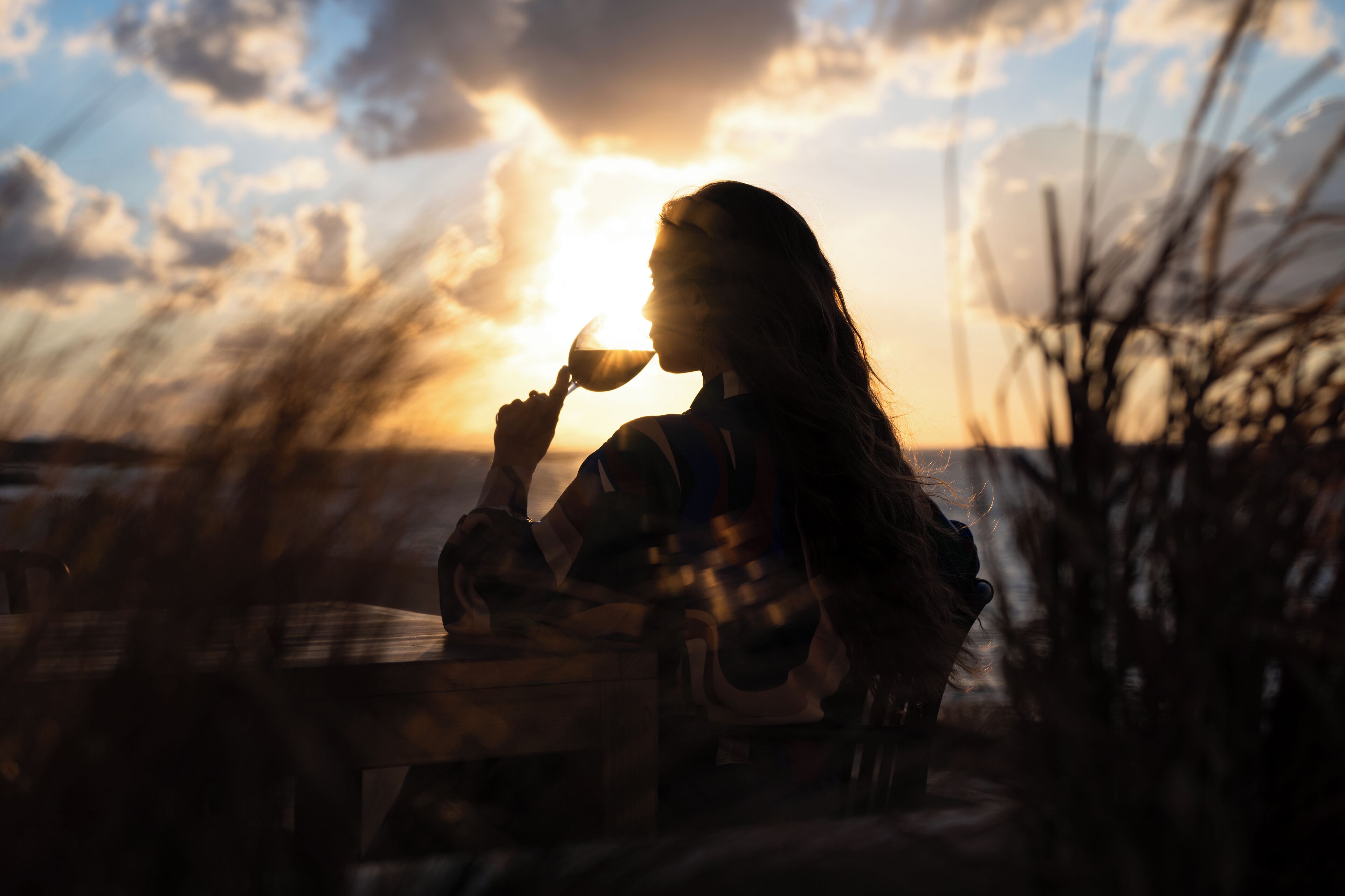 Una persona sentada a una mesa al aire libre durante el atardecer.