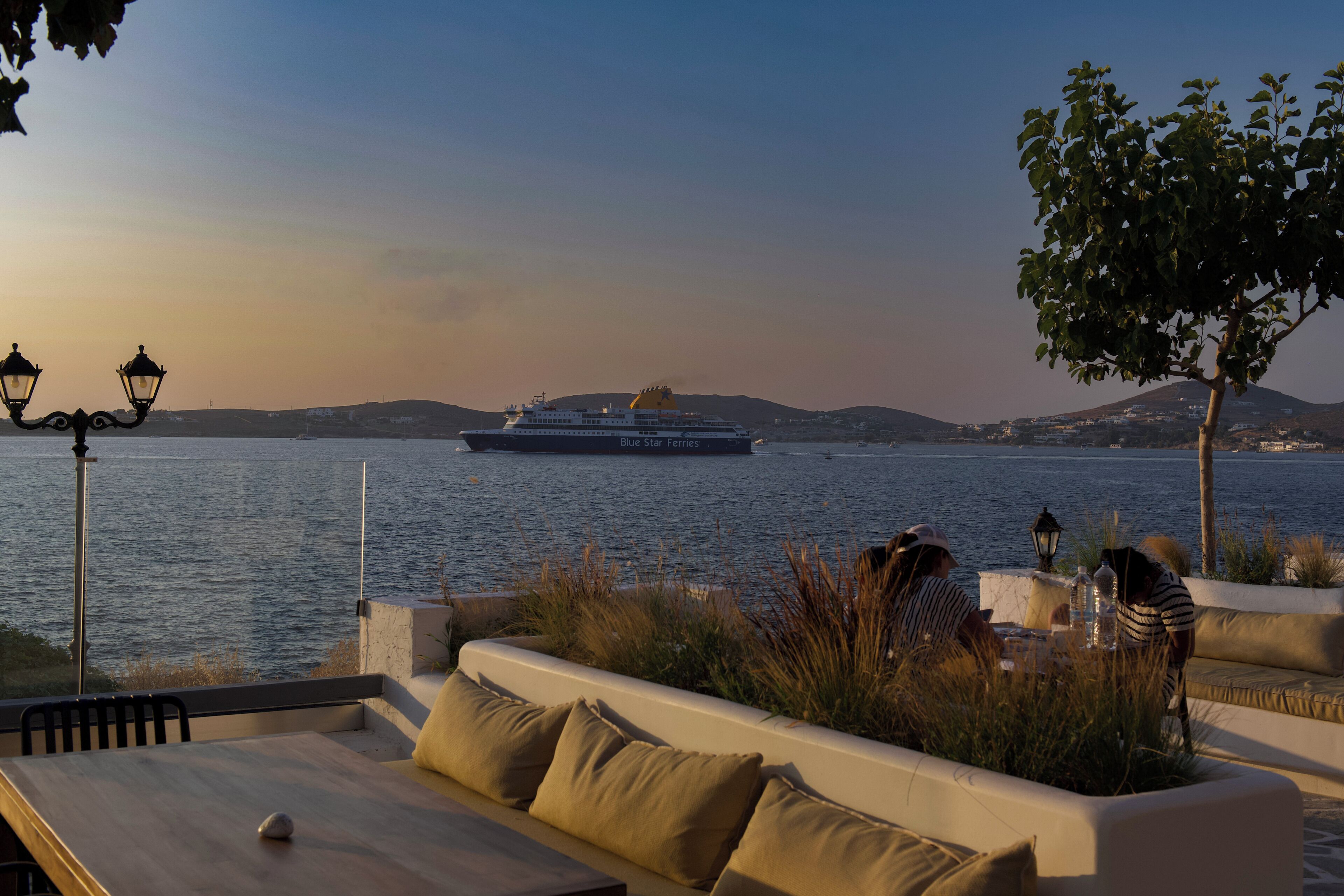 Zona de estar frente al agua, con vista a un crucero llamado Blue Star Ferries.