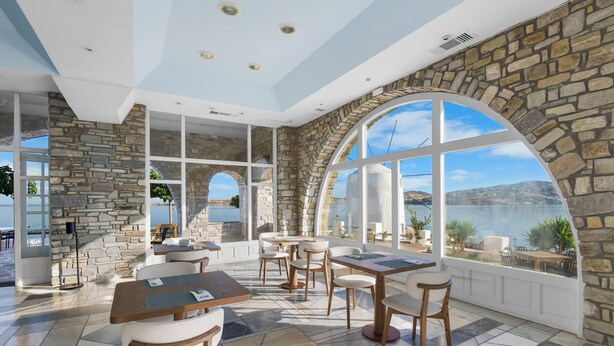 Un espacio interior amplio con paredes de piedra, ventanas arqueadas grandes y varias disposiciones de asientos.