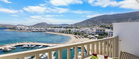 A balcony with a table, a view of a coastal town, and boats in the water.