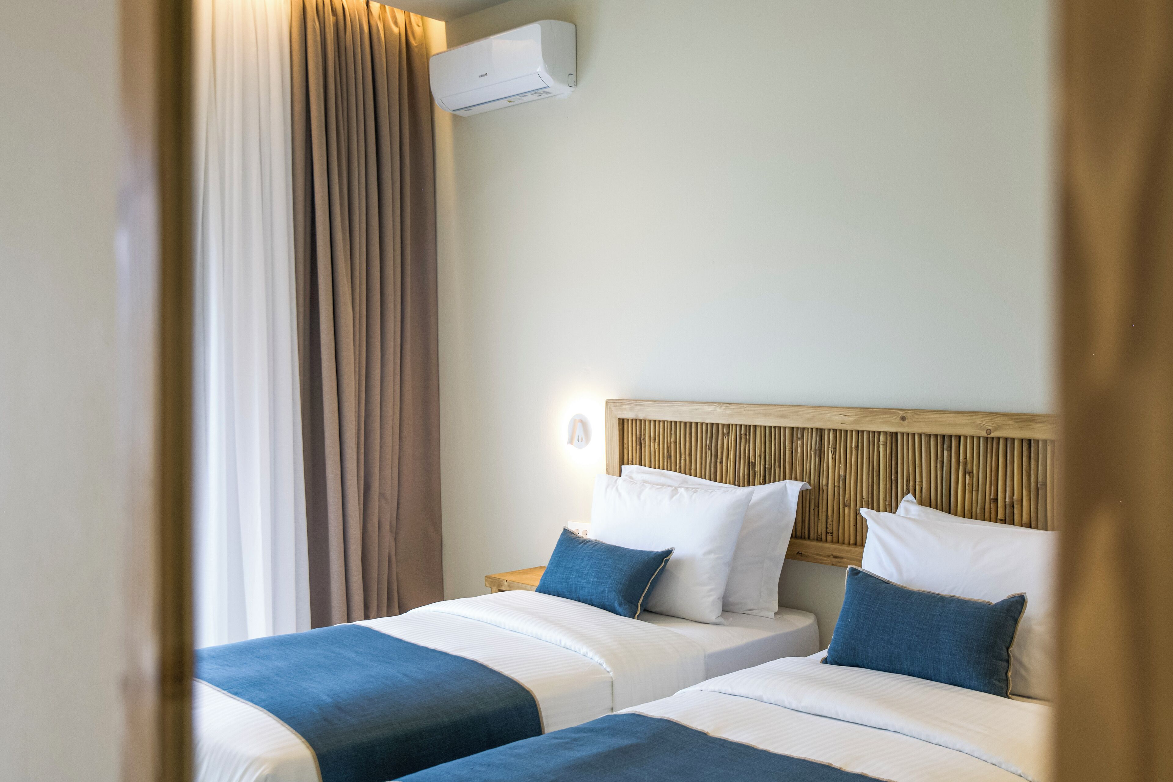 A hotel room with two beds, a wooden headboard, and an air conditioning unit.