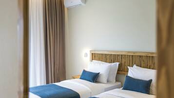 A hotel room with two beds, a wooden headboard, and an air conditioning unit.