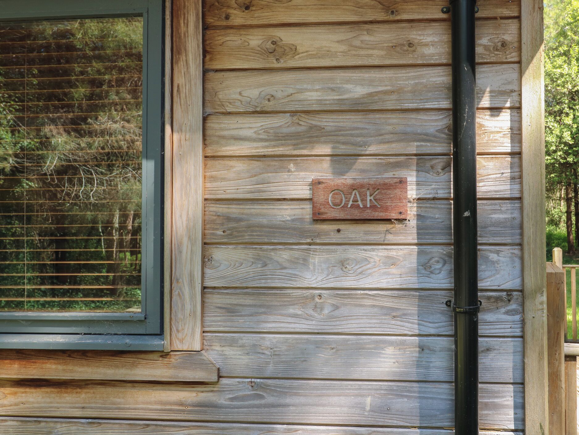 A wooden cabin with a window and a sign that reads "OAK".