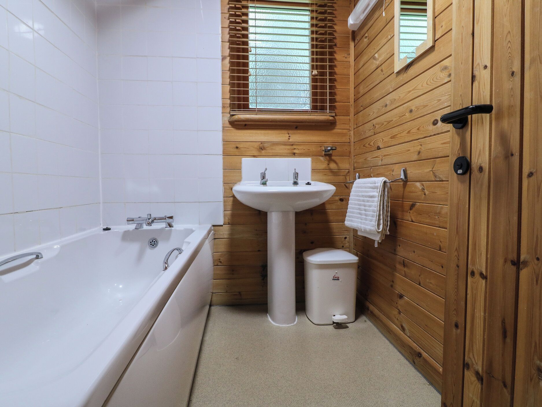 A bathroom with a white bathtub, a pedestal sink, and a toilet.