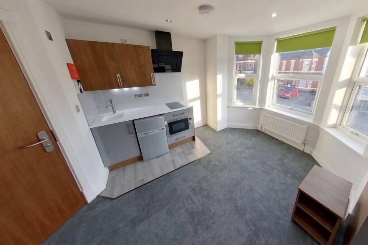 A compact kitchen with modern appliances, a built-in oven, and a window with a view of the street.