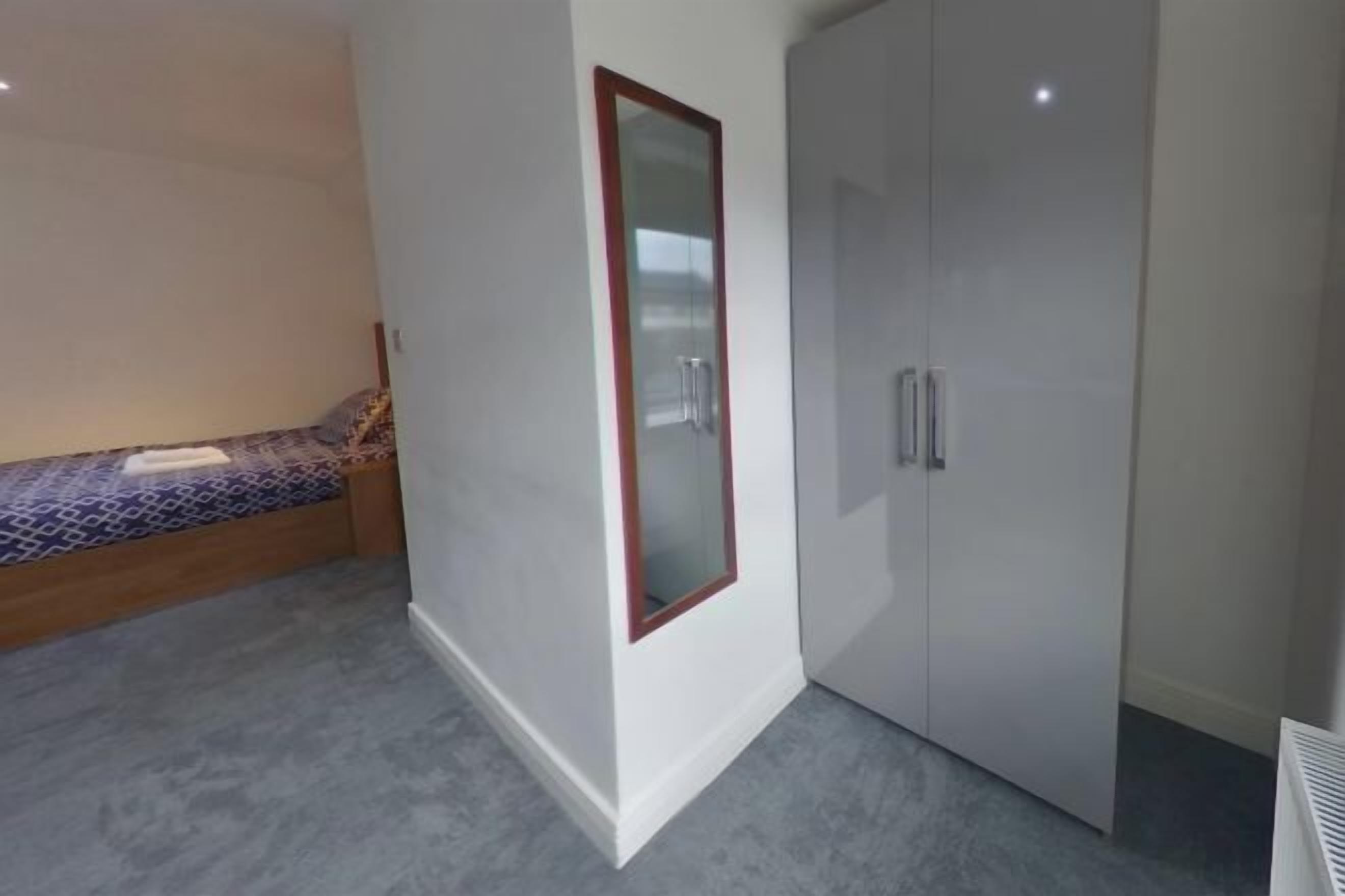 A bedroom with a bed, a wardrobe, and a small bench.
