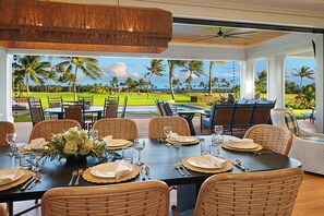 A dining area with a view of a golf course and ocean. - Perfection in Poipu: Brand new luxury home, ocean views, pool+spa (Koloa)
