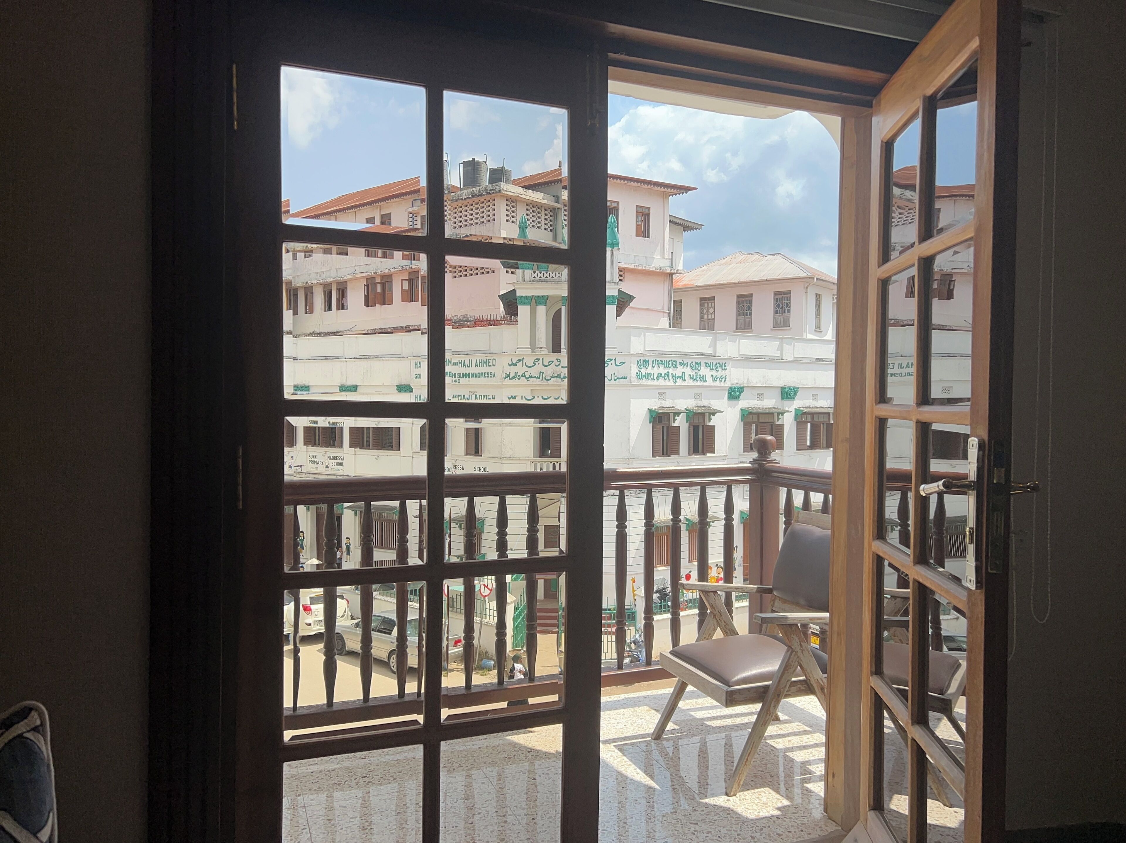 Un balcon donnant sur des immeubles, avec une chaise.