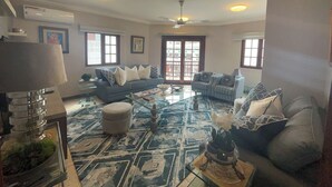 A living room with a sofa, armchairs, a coffee table, and a patterned floor. - Mango restaurant and apartment hotel (Zanzibar Town)