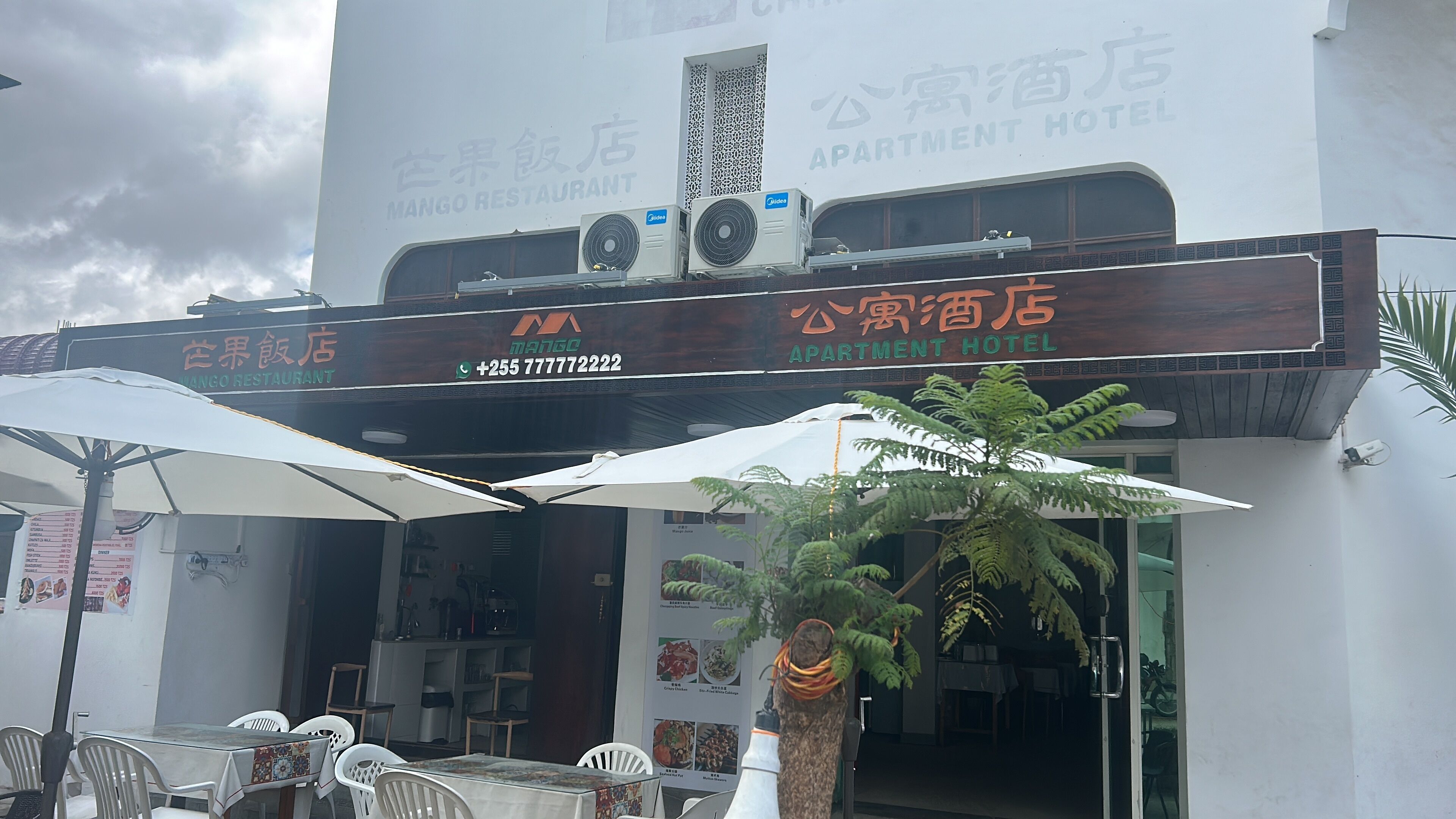 A Mango Restaurant and an Apartment Hotel with outdoor seating and umbrellas.