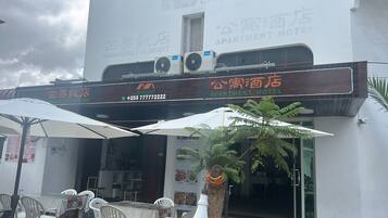A Mango Restaurant and an Apartment Hotel with outdoor seating and umbrellas.