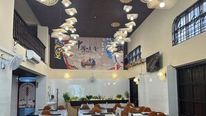 A spacious dining area with tables set for guests, a central stage, and decorative ceiling lights. - Mango restaurant and apartment hotel (Zanzibar Town)