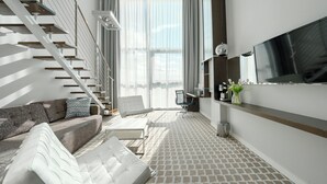 A modern living room with a staircase, a sofa, a coffee table, and a flat-screen TV mounted on the wall. - Apartamenty Sun & Snow Marine (Kolobrzeg)
