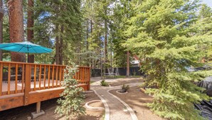 A wooden deck with a blue umbrella, surrounded by trees and a winding path. - Lake Haven- Spacious 5-bedroom, Kings Beach, 12 guests- pet friendly (Kings Beach)
