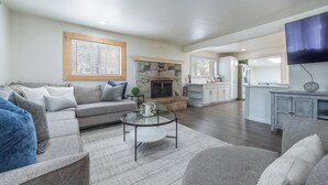 A modern living room with a stone fireplace, a glass coffee table, and a grey sofa. - Lake Haven- Spacious 5-bedroom, Kings Beach, 12 guests- pet friendly (Kings Beach)