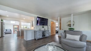 A modern living room with a grey sofa, a glass coffee table, and a flat-screen TV mounted on the wall. - Lake Haven- Spacious 5-bedroom, Kings Beach, 12 guests- pet friendly (Kings Beach)