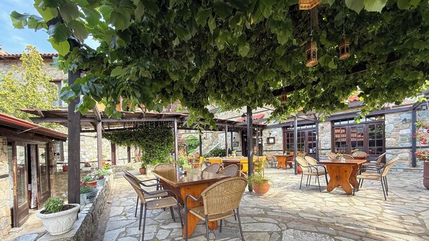 Un espace extérieur aménagé en terrasse, avec un sol en pierre, des meubles en osier et des plantes en pot.