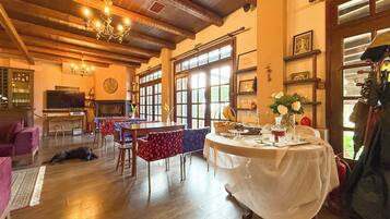 A spacious room with wooden floors, a dining table set for a meal, and a large window providing natural light.