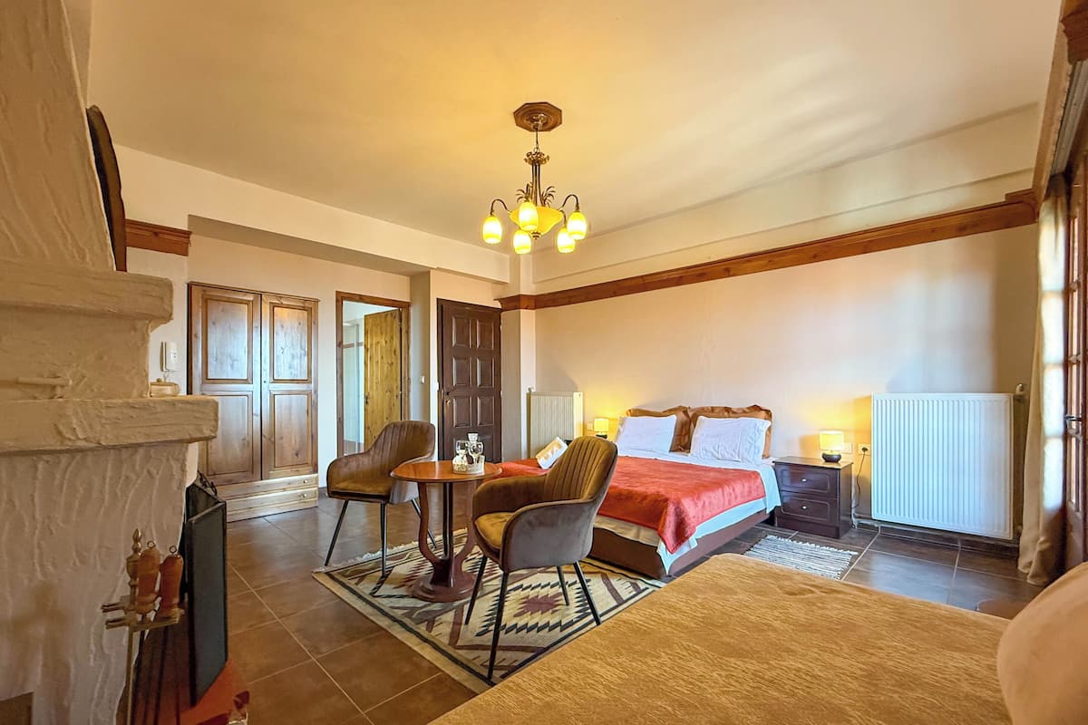 Une chambre d’hôtel avec un lit, un bureau et une chaise, une cheminée et un lustre.