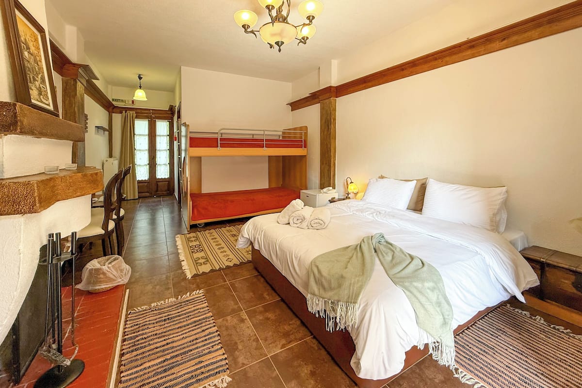 Une chambre avec un lit superposé, un bureau avec une chaise, un lustre et un tapis à motifs.